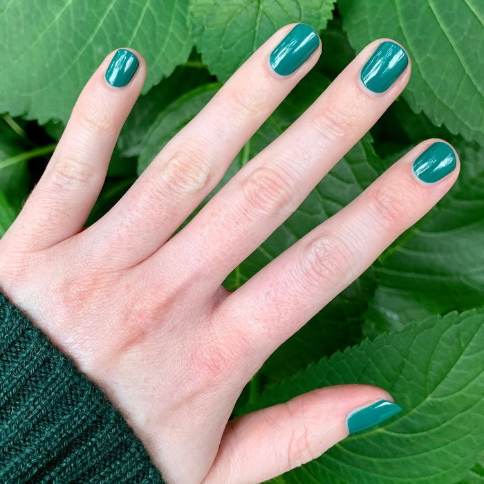 Hand displaying smooth, streak-free mani with Besties polish in a rich emerald green shade by Olive and June
