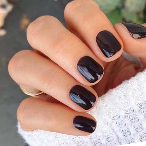 Close-up of hand with nails coated in CN polish showing a smooth, long-lasting manicure in deep sable brown shade