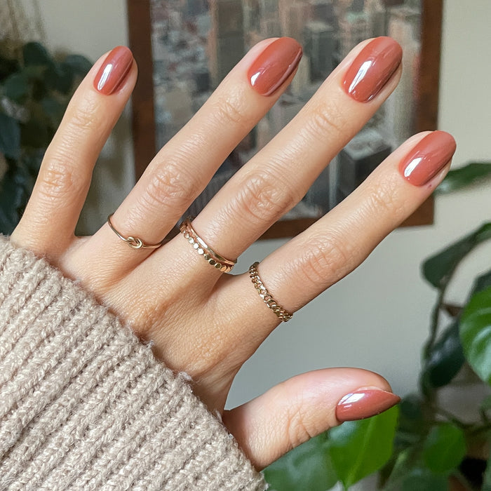 Cocoa Chrome - Press-On | Short | Round short rounded nails with dark chocolate chrome finish on hand wearing delicate rings