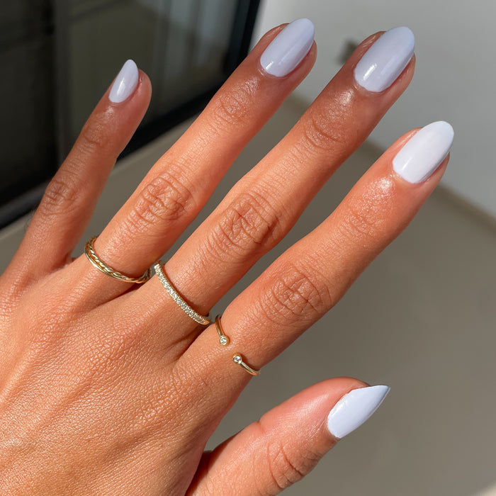 Hand with nails coated in Rink icy pastel blue quick dry polish showing a smooth at-home manicure look