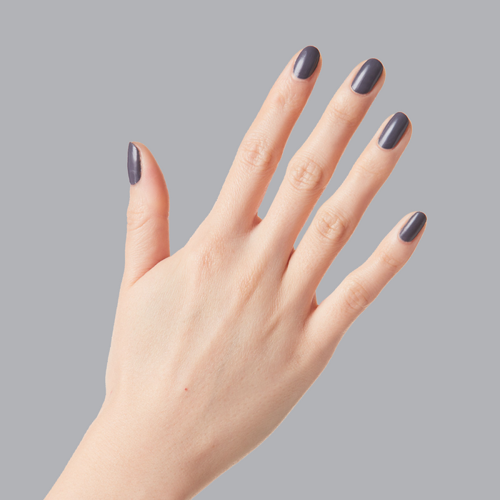 Hand displaying nails painted with 100% CHANCE gunmetal blue polish for a smooth, long-lasting manicure finish