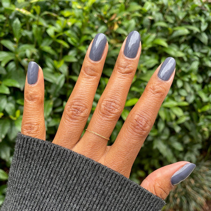 Hand with nails painted in 100% CHANCE gunmetal blue polish for a smooth and long-lasting manicure finish
