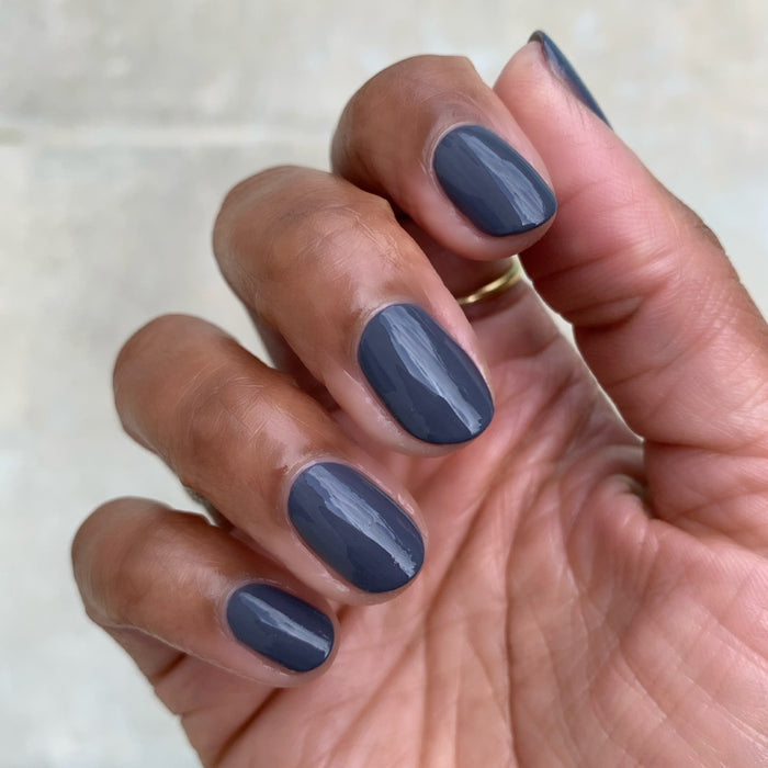 Hand showing nails polished in 100% CHANCE for a smooth, streak-free mani with rich gunmetal blue finish