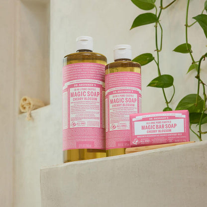 Dr. Bronner's Magic Soap Cherry Blossom bottles and bar on a shelf with a plant in the background