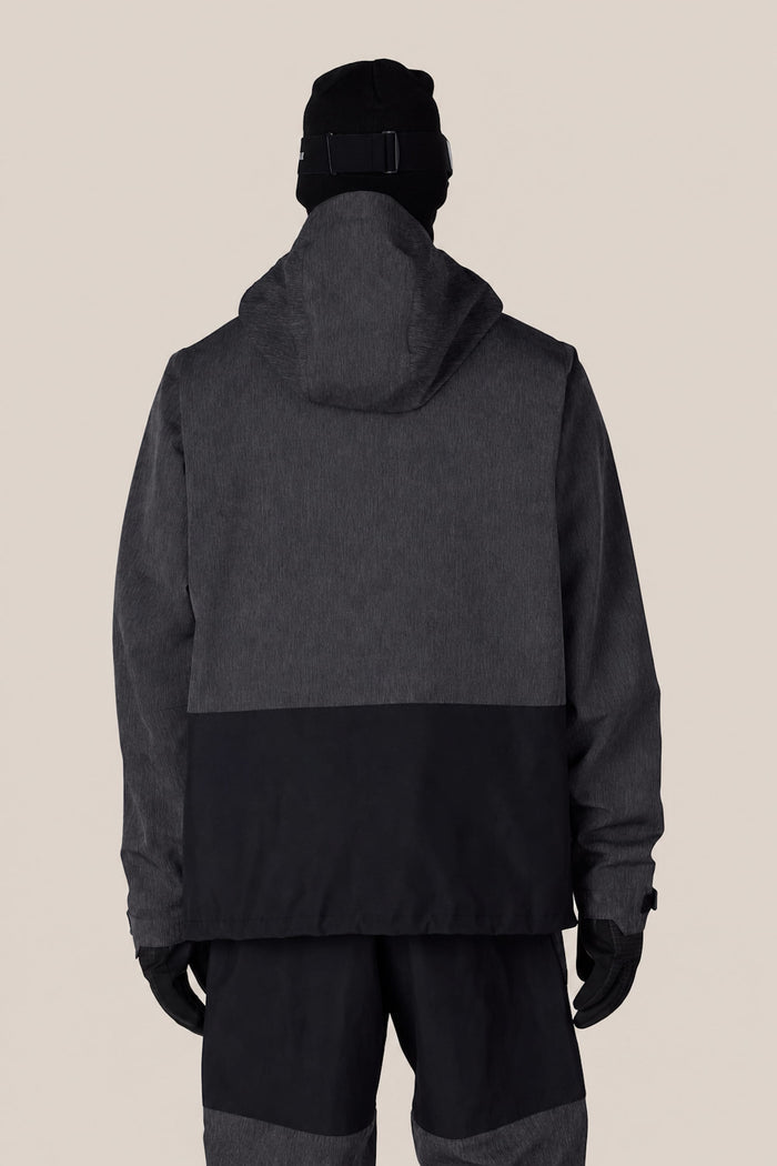 A person wearing the 686 Men’s Ghost™ 2.5L Anorak by 686, along with a black hat and gloves, is shown from the back against a plain beige background.
