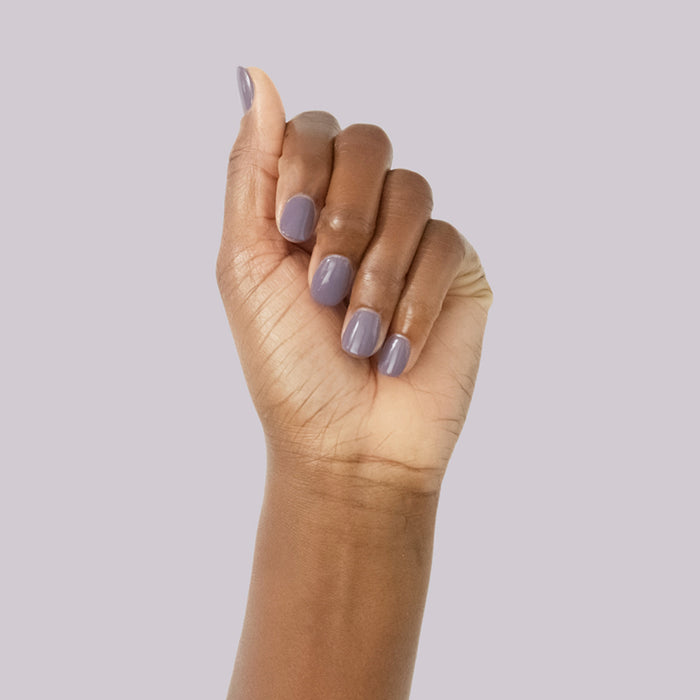 Hand with smooth glossy muted purple manicure showcasing Art Class nail polish on soft lavender background