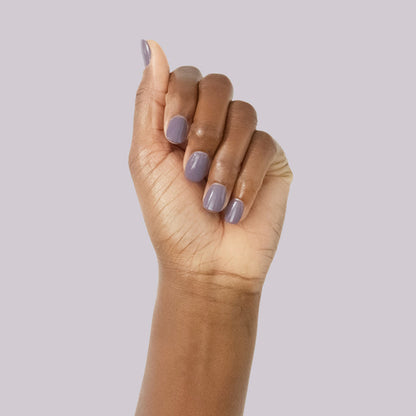 Hand with smooth glossy muted purple manicure showcasing Art Class nail polish on soft lavender background