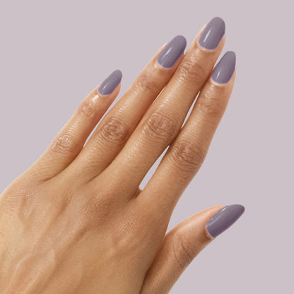 Hand with glossy muted eggplant manicure using Art Class polish on a soft lavender background