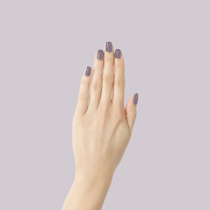 Hand with muted eggplant nails in Art Class polish showing a smooth manicure on a light lavender background