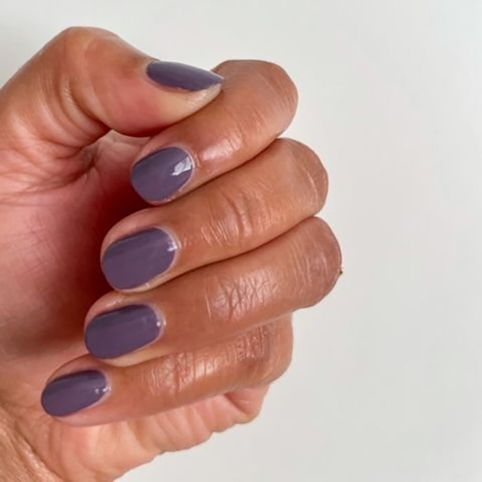 Hand with glossy muted eggplant manicure using Art Class nail polish on a clean white background