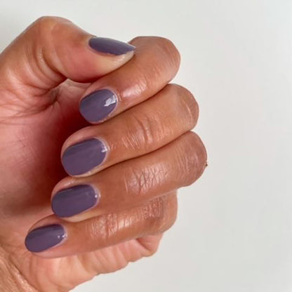Hand with glossy muted eggplant manicure using Art Class nail polish on a clean white background