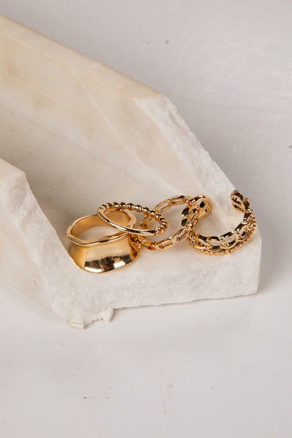 four gold rings on a white stone surface