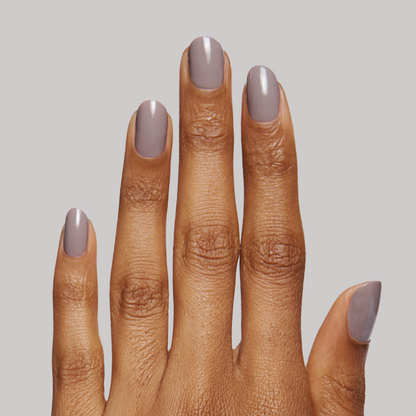 Hand with nails painted in warm grey AW shade showing glossy manicure against soft neutral background