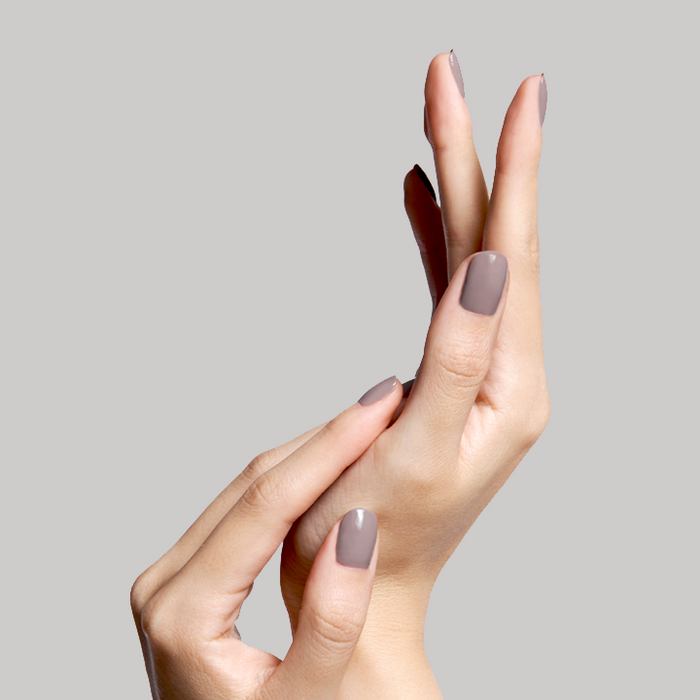 Hands with nails painted in AW warm grey showing a smooth, glossy manicure against a soft neutral background