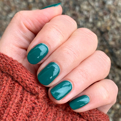 Hand with nails painted in glossy deep emerald green Besties polish showing a smooth, long-lasting manicure
