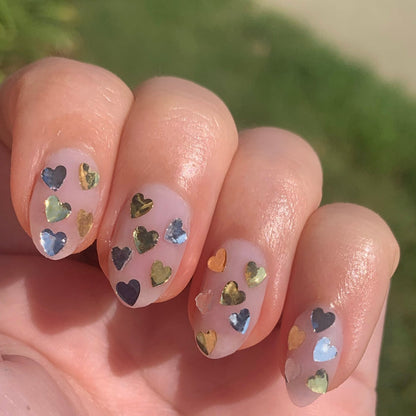 Fingers with a natural manicure featuring silver and gold heart confetti glitter using Biggest Fan polish by Olive and June