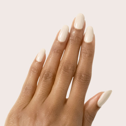 Hand with smooth manicure featuring Chemistry light almond cream polish on neutral pale background