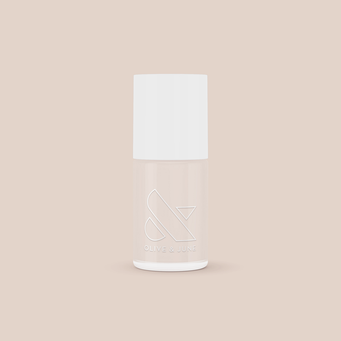 Bottle of Chemistry light almond cream nail polish by Olive and June on soft beige background