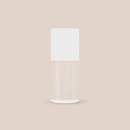 Bottle of Chemistry light almond cream nail polish by Olive and June on soft beige background