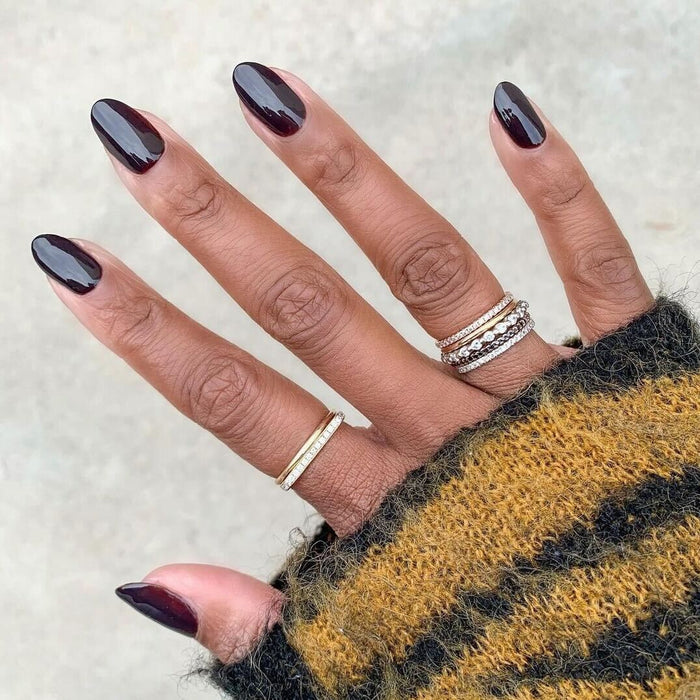 Hand with nails painted in deep glossy CN polish showing a smooth, long-lasting manicure on dark skin tone