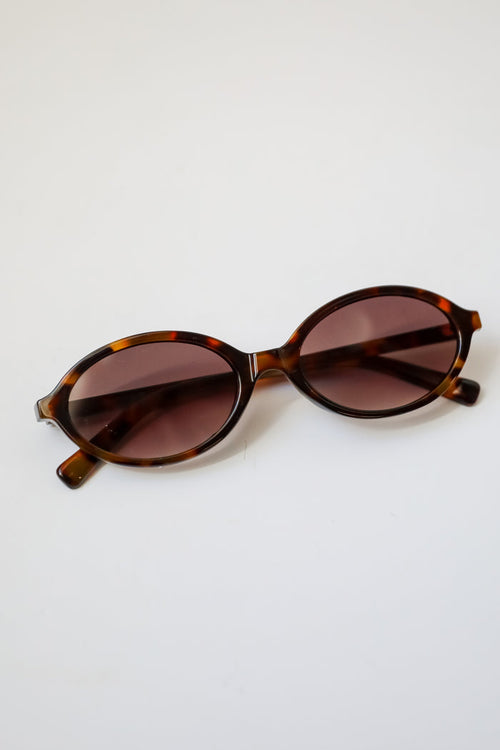 Sunglasses with tortoiseshell frame and brown lenses on a white background