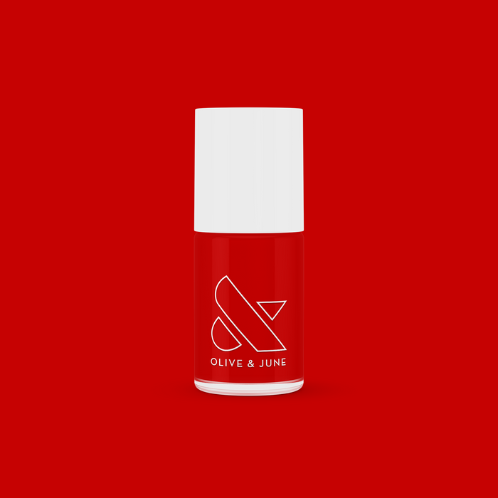 Olive and June CV nail polish bottle in bright cherry red with white cap on a vibrant red background