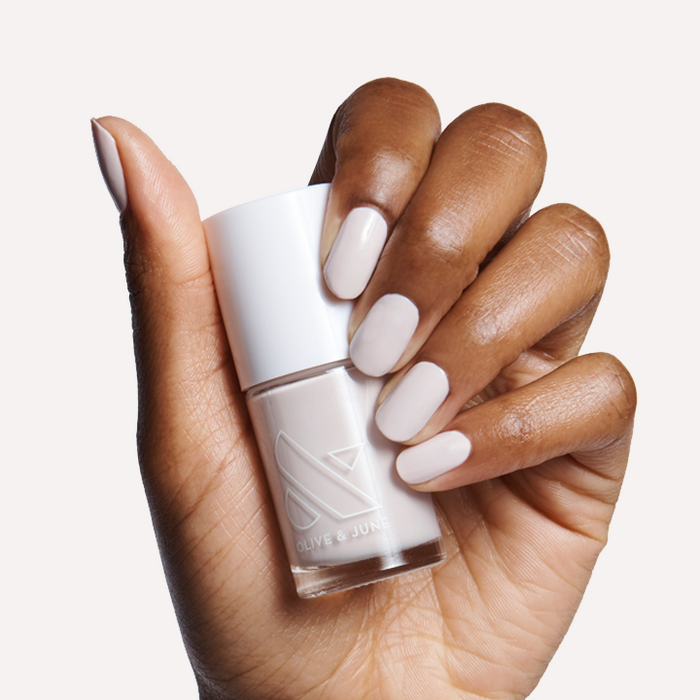 Hand with ECC polish in cool white grey holding bottle for a smooth, modern manicure on medium natural nails