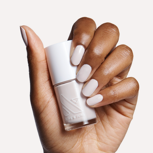 Hand with ECC polish in cool white grey holding bottle for a smooth, modern manicure on medium natural nails