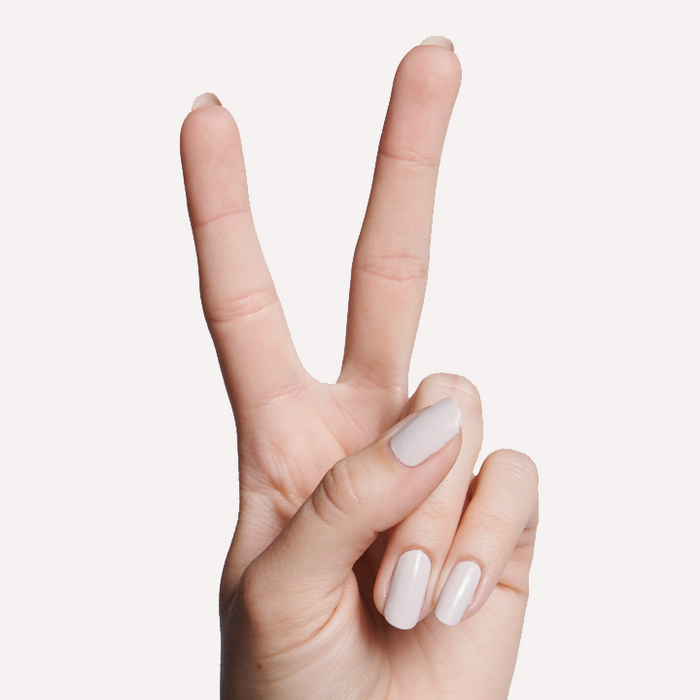Hand showing peace sign with nails painted in cool white grey ECC polish for a modern long-lasting manicure