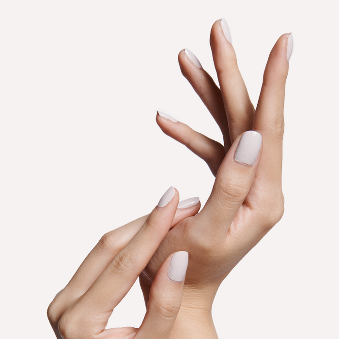 Two hands with neatly manicured nails painted in ECC cool white grey polish against a plain white background