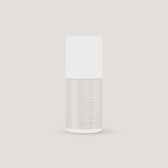 Minimalist bottle of ECC nail polish in soft white grey shade by Olive and June on neutral background for mani use