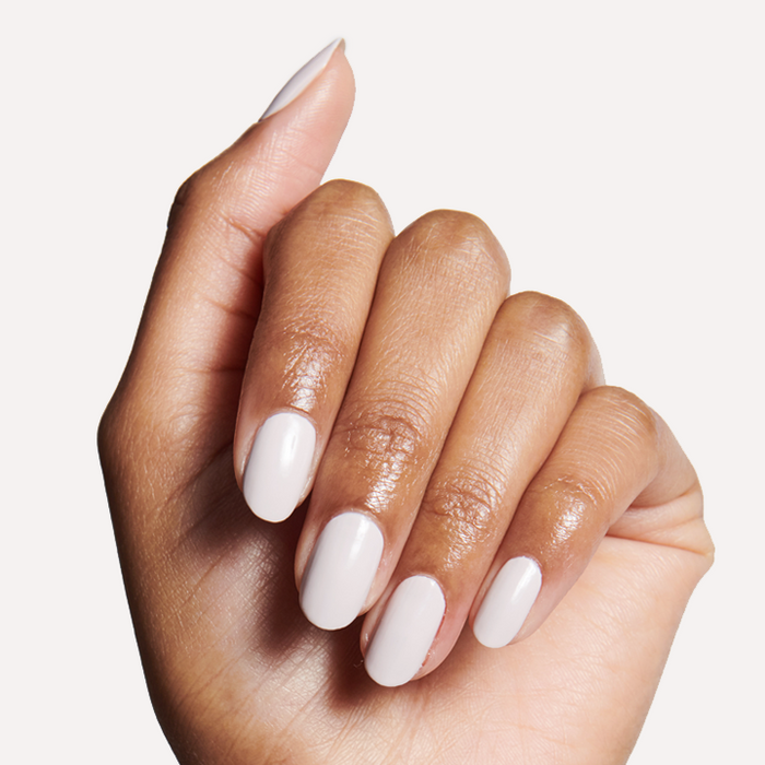 Hand with medium skin tone showing a smooth manicure with ECC long-lasting polish in cool white grey shade on neutral background