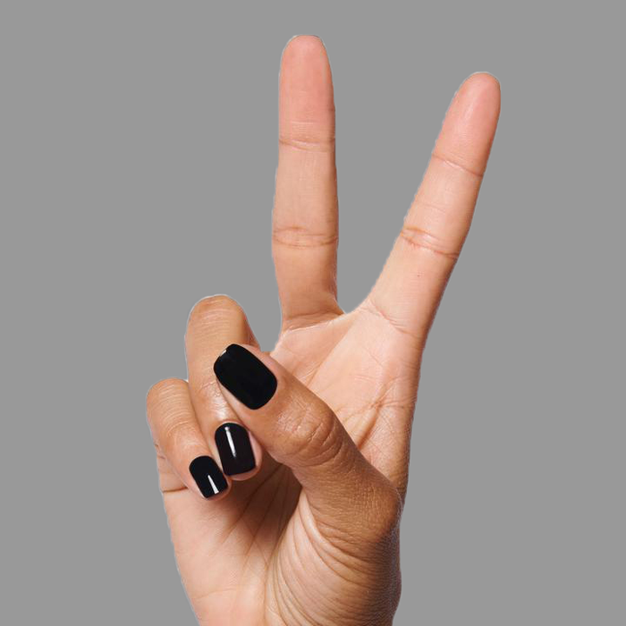 Hand with nails painted in deep black E+M polish by Olive and June showing a sleek manicure on a gray backdrop