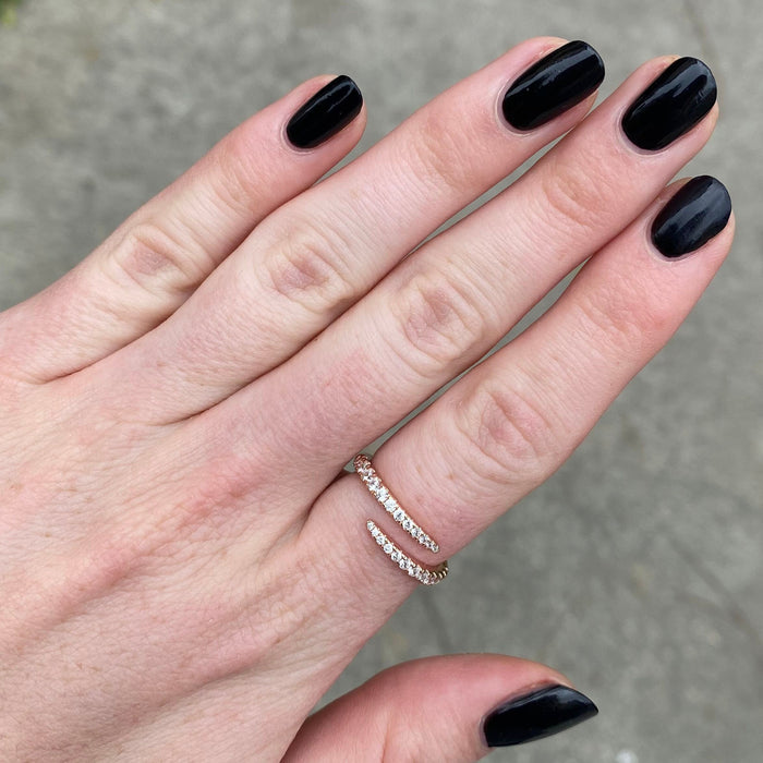 Hand featuring deep black E+M nail polish by Olive and June with a minimalist diamond ring on a neutral background