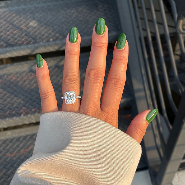 Hand outdoors with Geometry polish in hunter green on glossy nails next to metal stairs in natural light