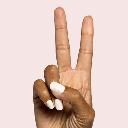 Heart Shower | Extra Short | Squoval - Tab Press-On neutral short nails with subtle pink heart accents on hand making peace sign