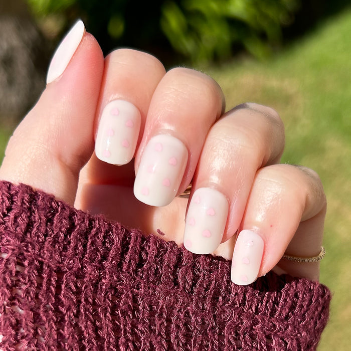 Heart Shower | Extra Short | Squoval - Tab Press-On neutral toned nails with tiny soft pink hearts worn with burgundy sweater outdoors