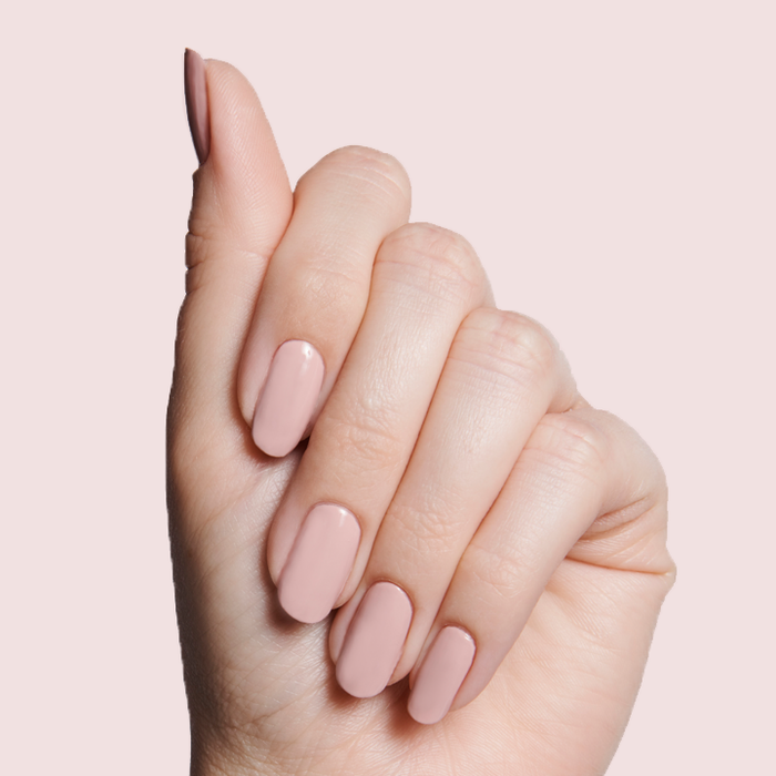 Hand with nails painted in HZ rosy neutral polish showing a smooth manicure on a soft pink background