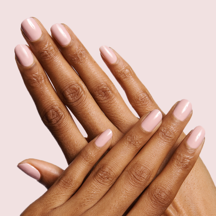 Hands with nails painted in HZ rosy neutral polish showing a smooth and feminine mani on pale pink background