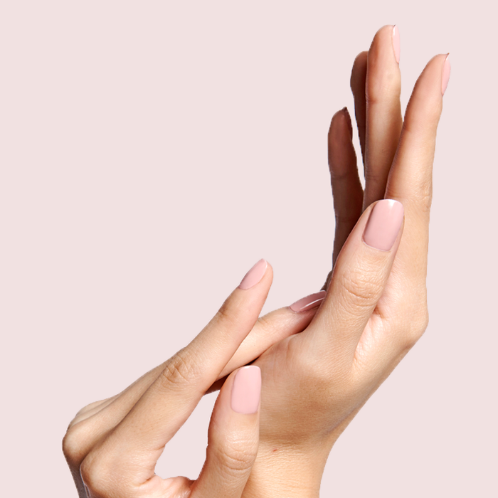Hands with nails polished in HZ rosy neutral shade showing a smooth and elegant manicure on a soft pink background