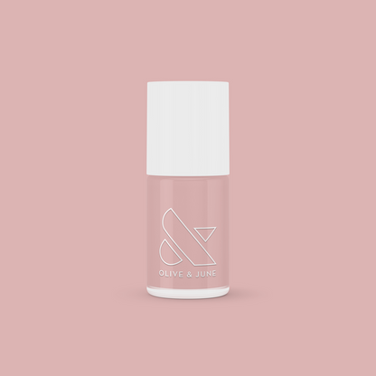HZ nail polish bottle by Olive and June in a soft rosy neutral shade on a muted pink background