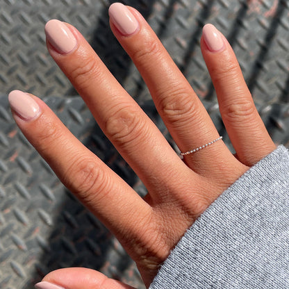Hand with nails polished in HZ rosy toned neutral shade showing a smooth manicure in natural light
