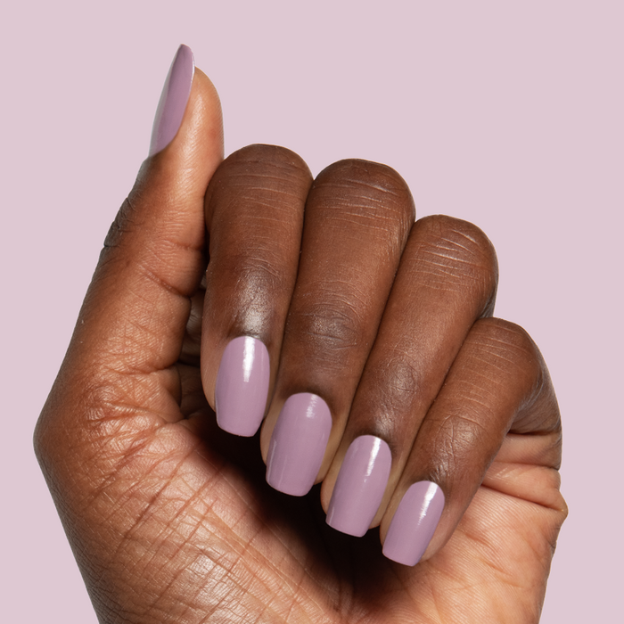Hand with glossy midtone mauve manicure using I Mani in Meetings polish against soft pink background