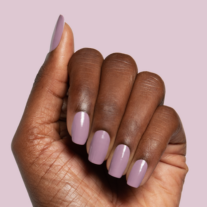 Hand with glossy midtone mauve manicure using I Mani in Meetings polish against soft pink background