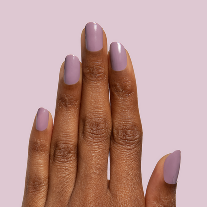 Hand with glossy midtone mauve manicure wearing I Mani in Meetings polish against soft purple background