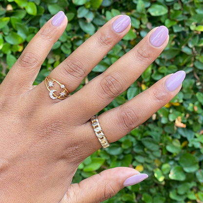 Hand with glossy purple midtone mauve manicure using I Mani in Meetings nail polish against green leafy background