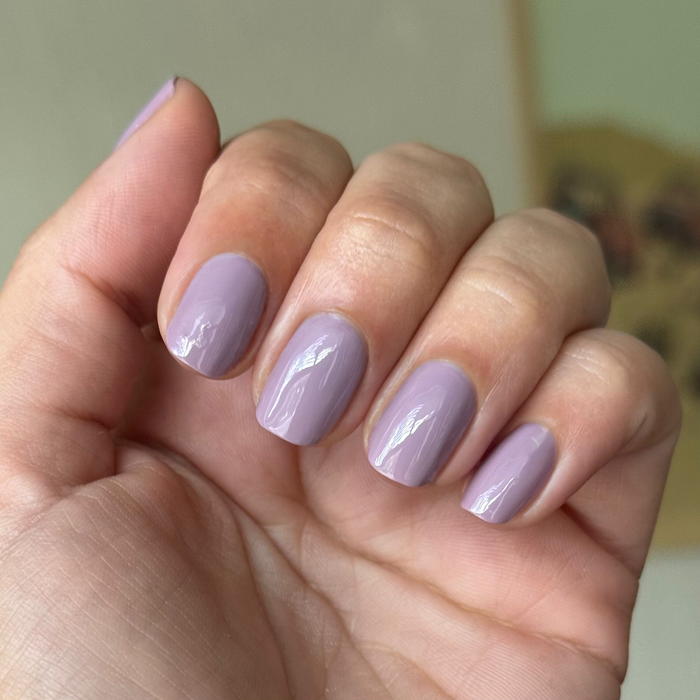 Hand displaying a glossy mauve manicure with I Mani in Meetings polish in an indoor setting close-up