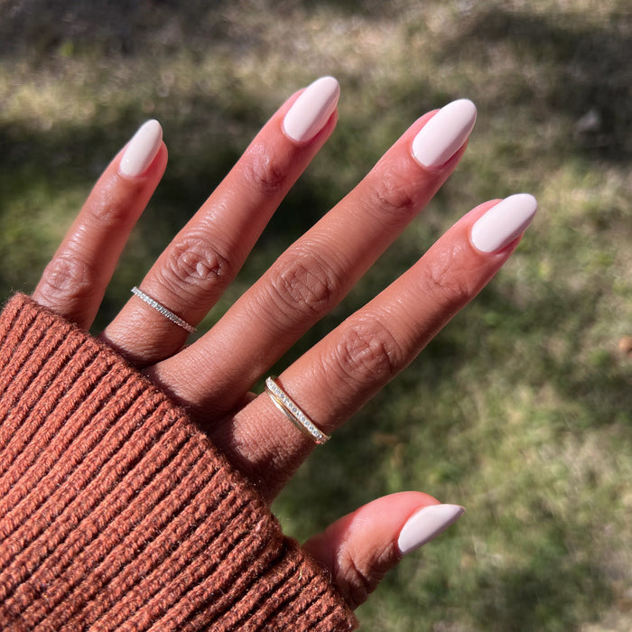 Hand with warm brown skin wearing It's Chilly! long-lasting gel polish manicure in cozy neutral beige shade outdoors