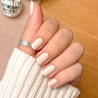 Hand with pale skin tone wearing It's Chilly! quick dry gel polish manicure in a cozy neutral beige shade indoors