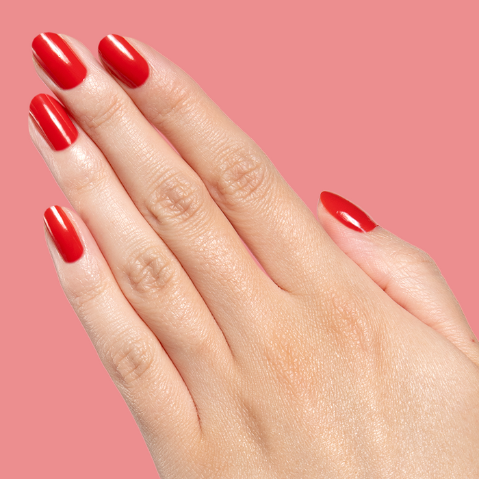 Hand displaying bright orange-red Let’s Circle Back gel polish manicure on pink background with glossy finish